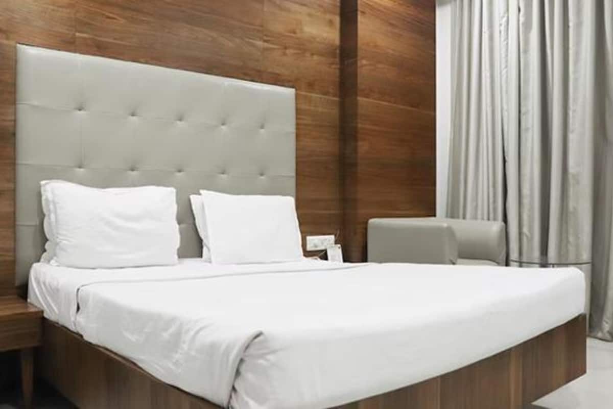 A modern bedroom with a large bed, wooden headboard, and a nightstand.