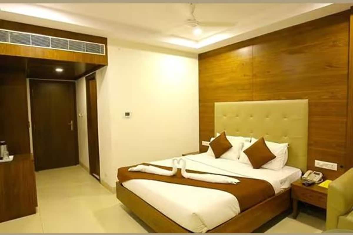 A hotel room with a large bed, a bedside table with a phone, and a chair.