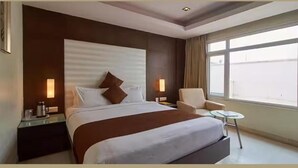 Una habitación de hotel con una cama grande, una silla, una mesita y una ventana con vistas.