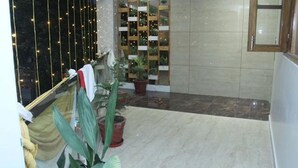 A room with a large window, a potted plant, and a wooden shelf with plants. - Fabhotel Prime The Daffodils (Dehradun)