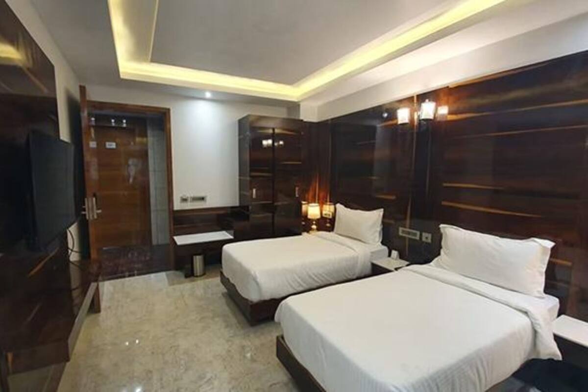 Quarto de hotel com duas camas, televisão e um minibar.