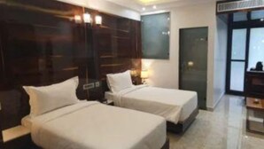 A modern hotel room with two beds, a large mirror, and a view of the city. - Fabhotel Prime The Daffodils (Dehradun)