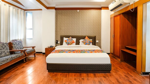 A bedroom with a large bed, a nightstand, a sofa, and a wardrobe. - Fabhotel Silver Inn Ii (Nashik)
