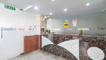 A hotel reception area with a marble counter, an exit sign, and a reception desk.