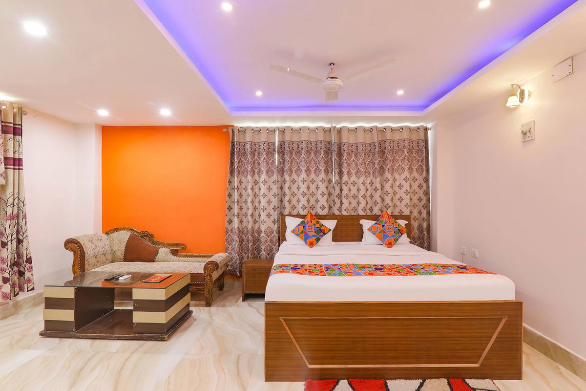 A bedroom with a bed, a sofa, a coffee table, and a ceiling fan.
