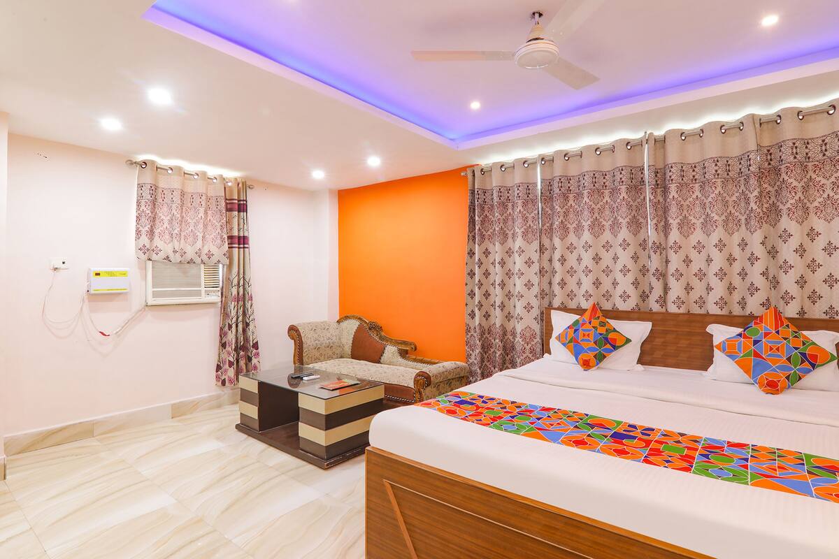 A bedroom with a bed, a sofa, a small table, and a ceiling fan.