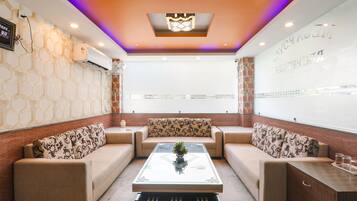 A modern lounge area with a glass coffee table, patterned sofas, and a decorative ceiling light.