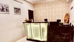 Un espace d’accueil doté d’un comptoir en marbre, de tableaux encadrés accrochés au mur et d’un papier peint à motifs.
