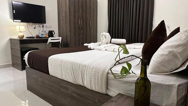 Une chambre d’hôtel moderne équipée d’un grand lit, d’un bureau, d’une télévision à écran plat et d’une plante.