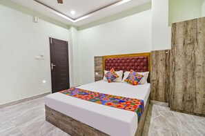 A neatly arranged bedroom with a bed, a wooden wardrobe, and a door.
