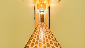 Et hotels korridor med et skakmønstret gulv, lyse vægge og et centralt lysarmatur.