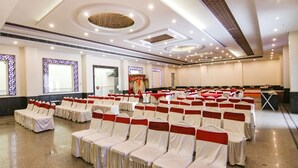 A banquet hall with rows of chairs covered in white and red sashes, a stage with a podium, and a long table with a red tablecloth. - Fabhotel Jalandhar Corporate Suites (Jalandhar)
