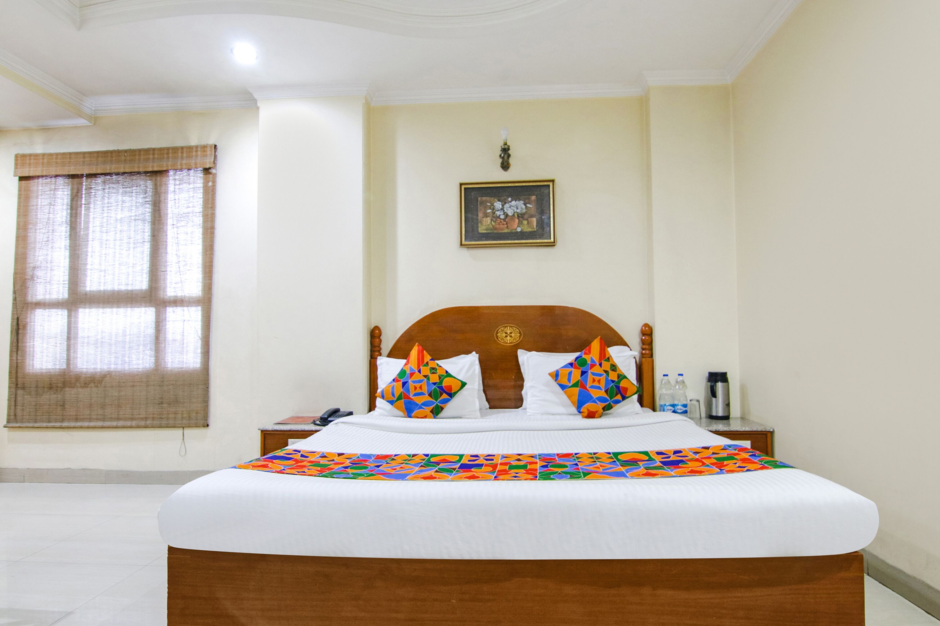 A neatly made bed with a colorful quilt, a wooden headboard, and a framed picture on the wall.