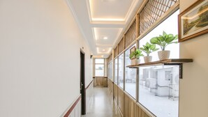A hallway with wooden paneling, a door at the end, and a window with potted plants. - Fabhotel Jalandhar Corporate Suites (Jalandhar)