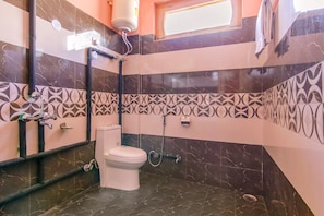 Une salle de bain équipée de toilettes, d’une douche et d’un sèche-mains.