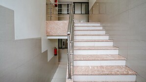 A modern staircase with marble steps and a metal railing, leading to an upper floor. - Fabhotel Konar Inn (Navi Mumbai)
