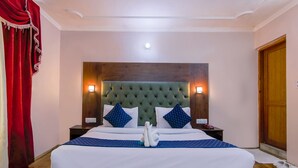 Habitación de hotel con una cama grande, cabecero de madera, dos mesitas de noche y una cortina roja.