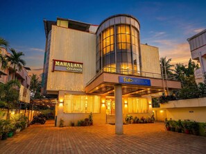Un hotel de diseño moderno, con fachada de vidrio curvo y un letrero que dice 'MAHALAYA Residency'.