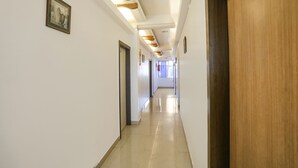 Un pasillo largo y estrecho con paredes blancas, puertas de madera e iluminación empotrada.