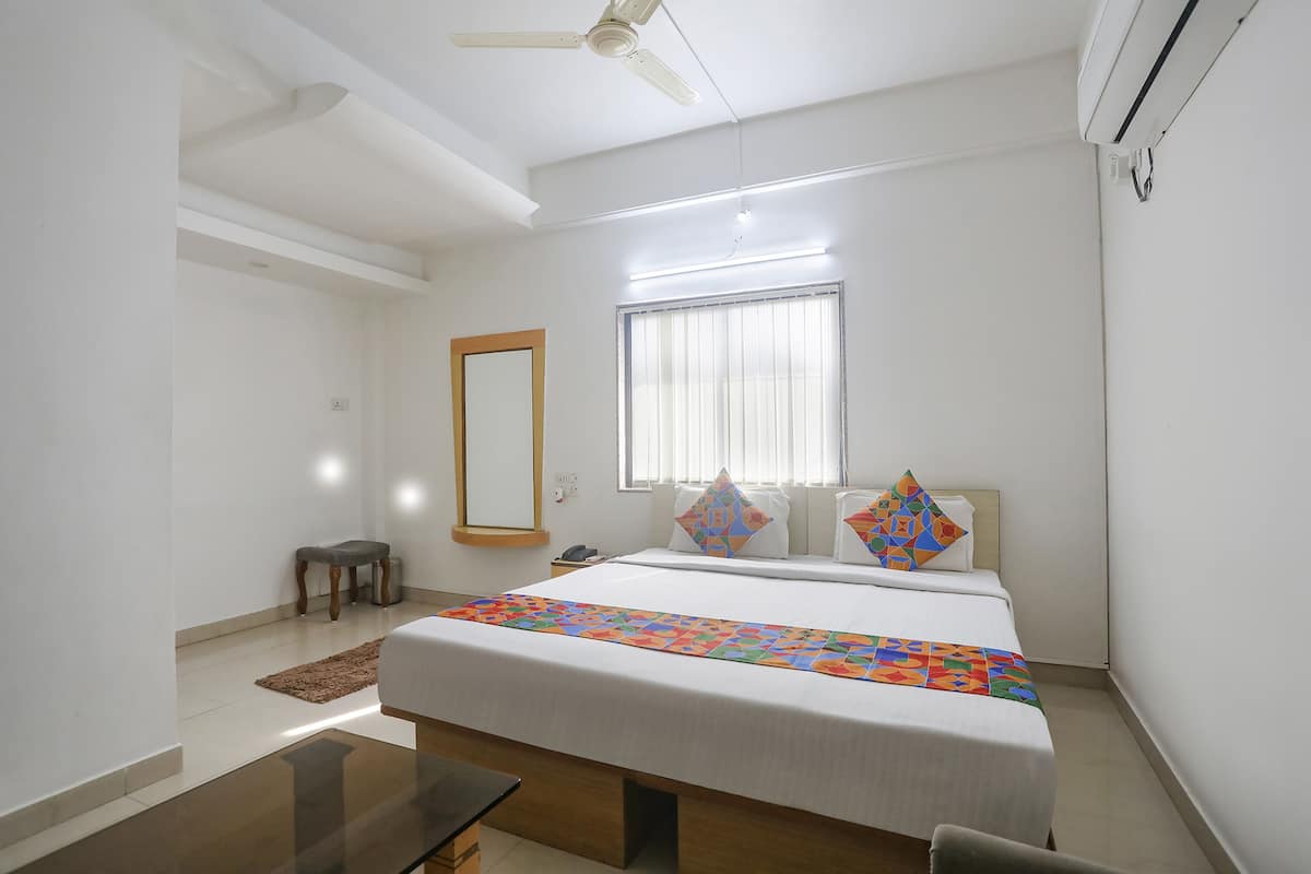 A bedroom with a bed, bedside table, nightstand, window, and ceiling fan.