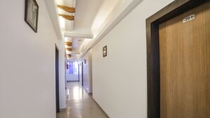 Un pasillo con puerta de madera marcada '201', paredes blancas y suelo de baldosas.