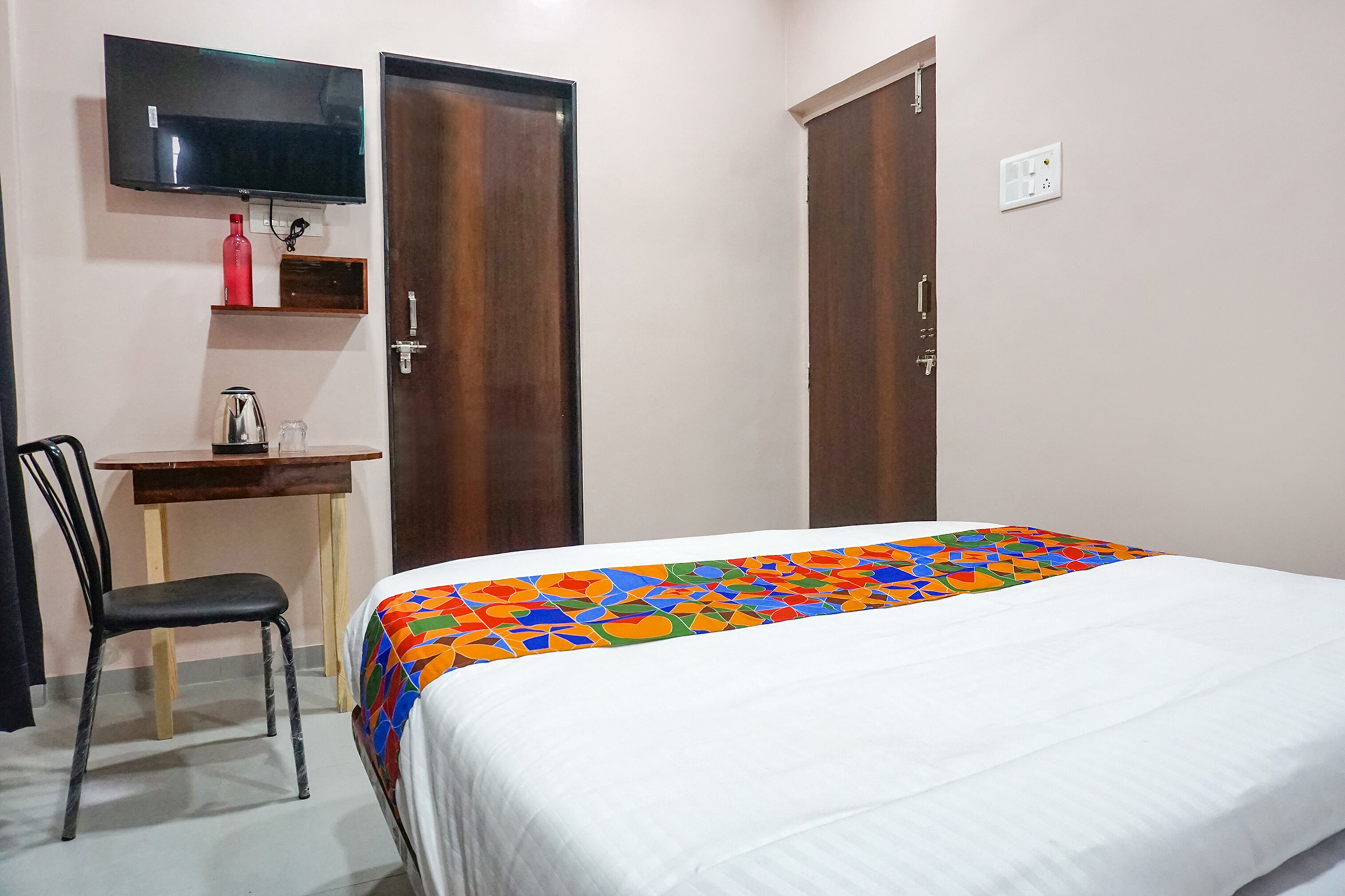 Ein Hotelzimmer mit einem Bett, einem Schreibtisch mit Stuhl, einem an der Wand befestigten Fernseher und zwei Kleiderschränken.