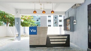 A reception desk with a 'Via' sign, a ceiling fan, and a view of buildings and trees. - Fabhotel Skyline I (Pune)