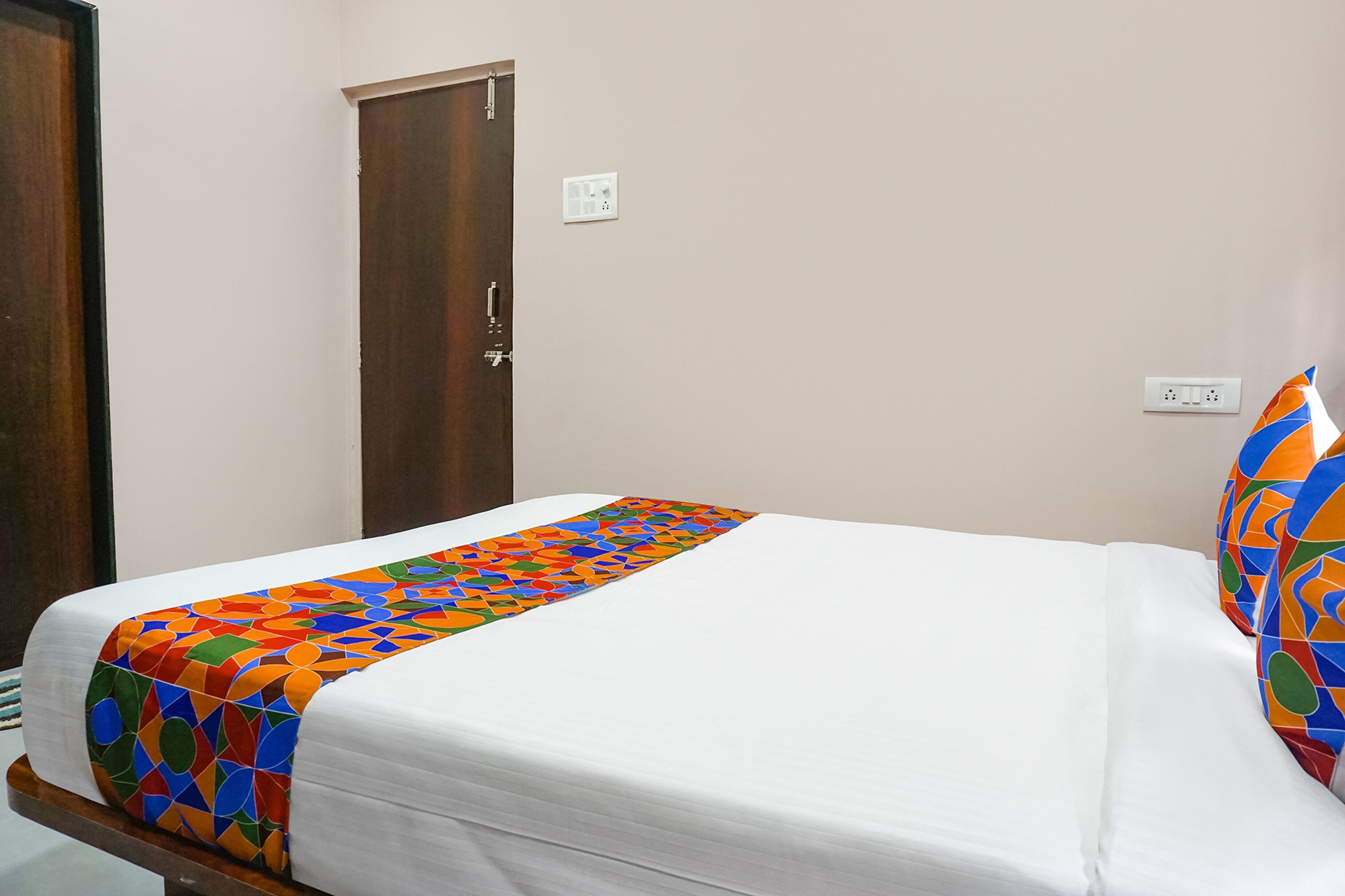 A neatly made bed with a colorful geometric-patterned bedspread and matching pillow.