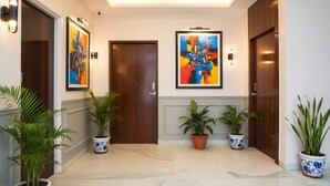 A hallway with marble flooring, wooden doors, and potted plants. - Fabhotel Skyline I (Pune)