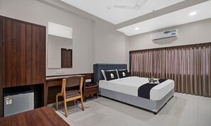 A modern hotel room with a large bed, a desk, a chair, and a wardrobe. - Fabhotel Prime Raajpath (Vadodara)