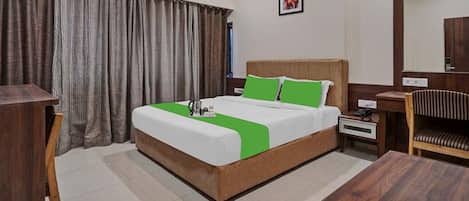 A hotel room with a bed, a nightstand, a chair, a desk, and a window with curtains.