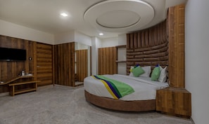 Quarto moderno com cama curva, paredes de painel de madeira, TV de tela plana e estante embutida.