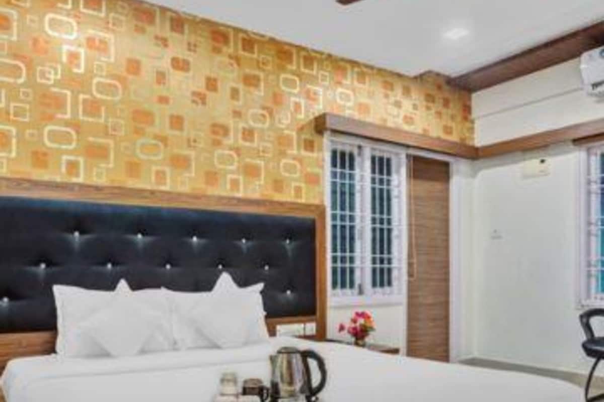 Une chambre avec un grand lit, un ventilateur de plafond et un mur décoré de motifs.
