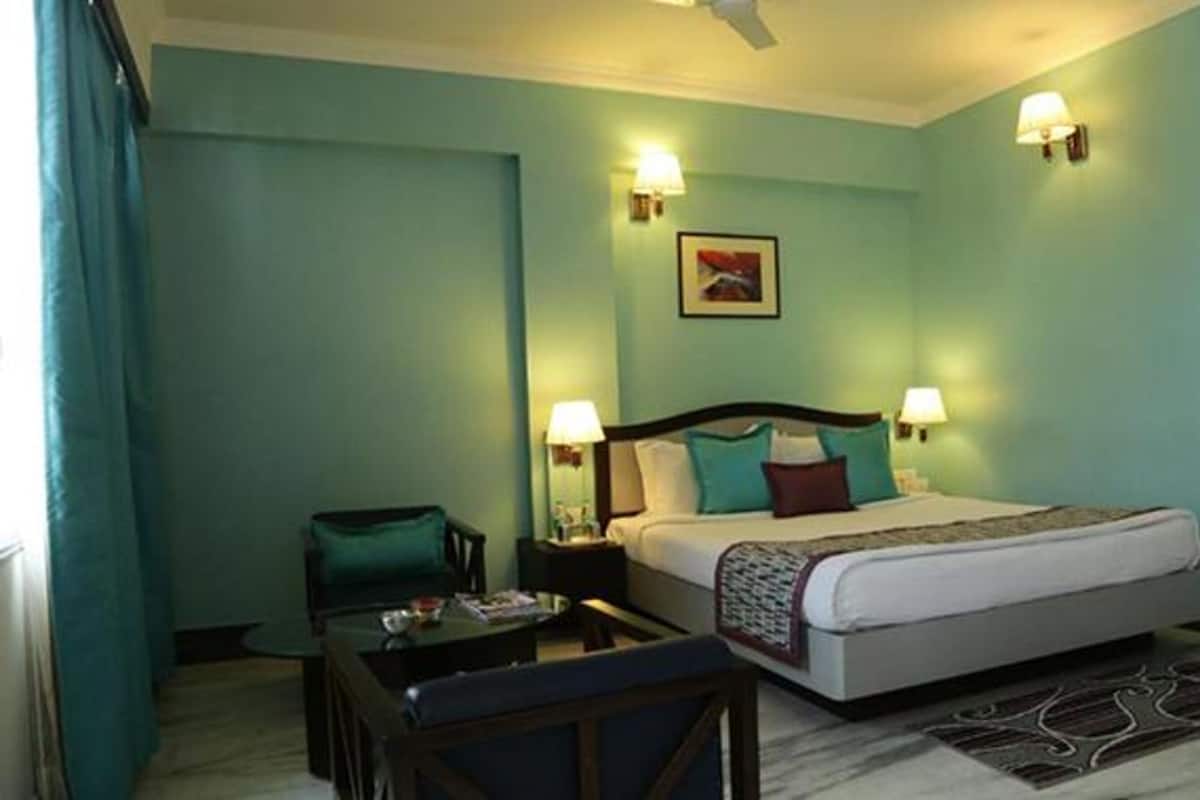 A hotel room with a bed, bedside lamps, a desk, and a chair.