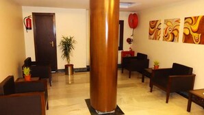 Un vestíbulo de hotel con una gran columna de cobre, mobiliario de madera y arte abstracto en las paredes.