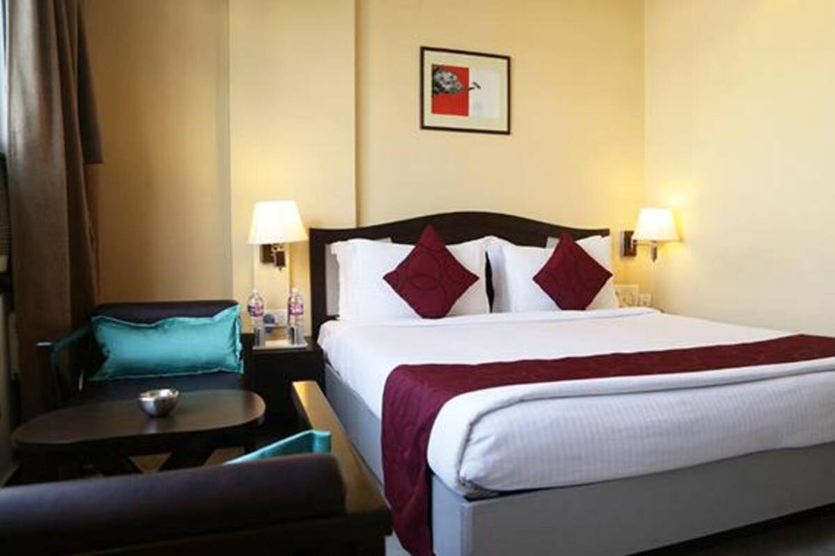 A hotel room with a bed, two bedside lamps, a nightstand, a chair, and a small table.