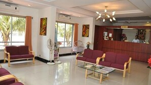 A reception area with a reception desk, two sofas, a glass coffee table, and artwork on the walls. - Fabhotel Prime Kb'S Grand (Rahata)