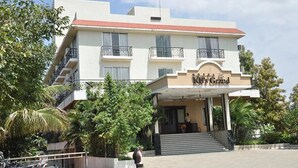 A hotel named "KB's Grand" with a modern architectural design, featuring a prominent entrance, multiple balconies, and lush greenery around the property. - Fabhotel Prime Kb'S Grand (Rahata)