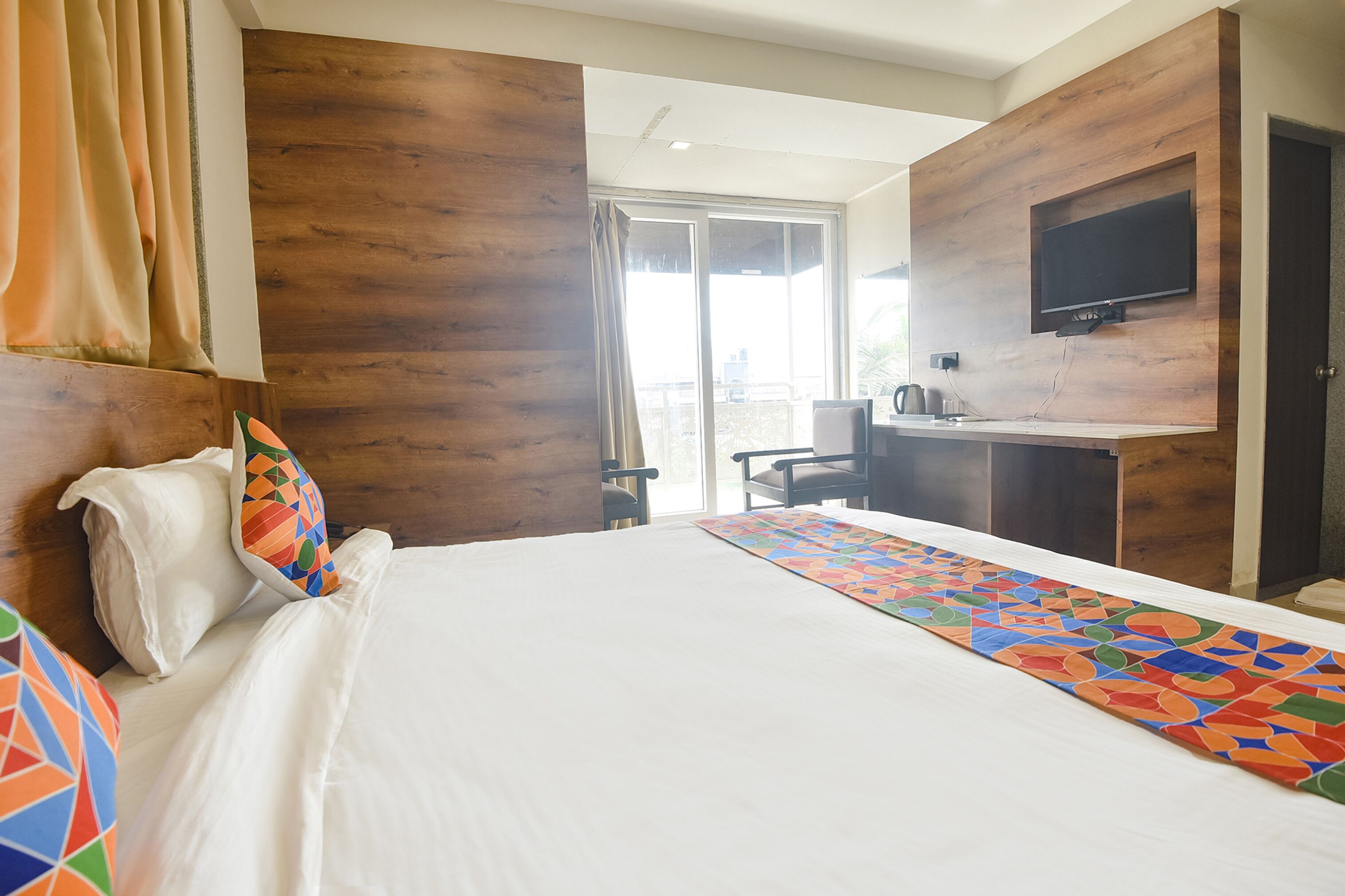 Una habitación de hotel con una cama, un escritorio y un televisor montado en la pared.