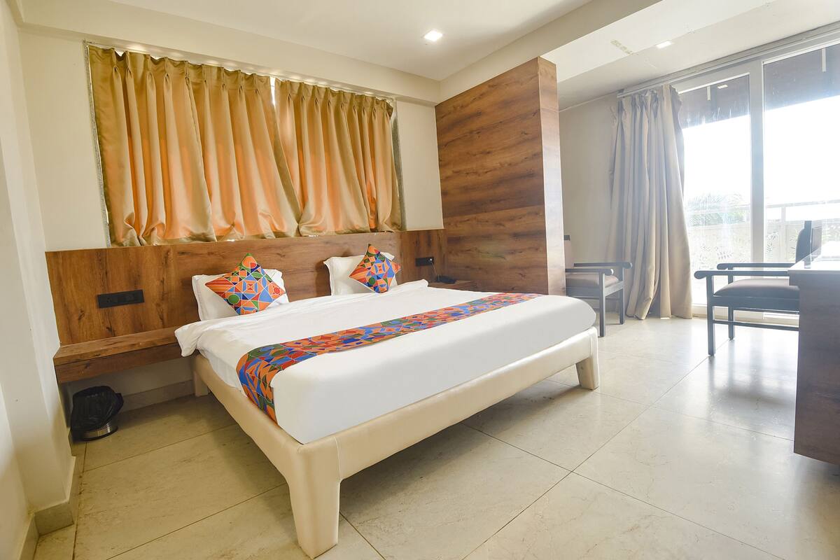 Una habitación de hotel con una cama grande, un cabecero de madera, un escritorio y una silla.