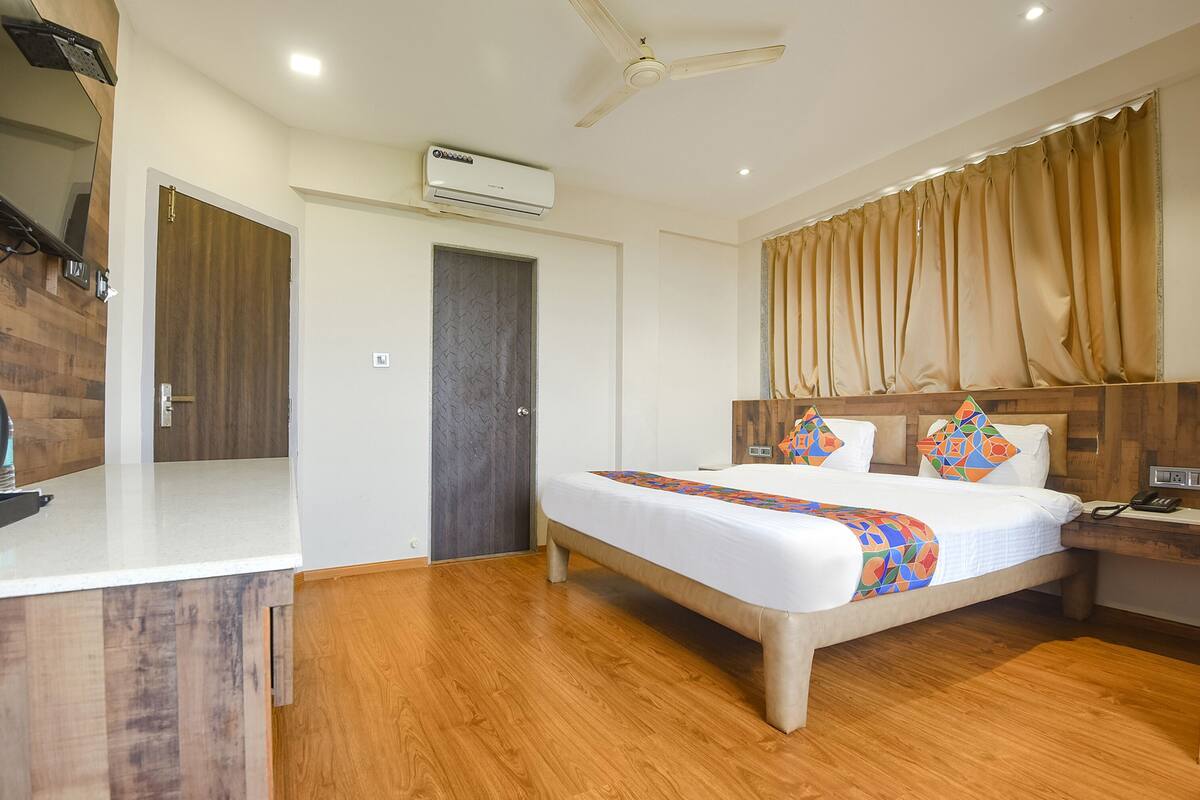 Habitación de hotel con cama, mesita de noche y un equipo de aire acondicionado.