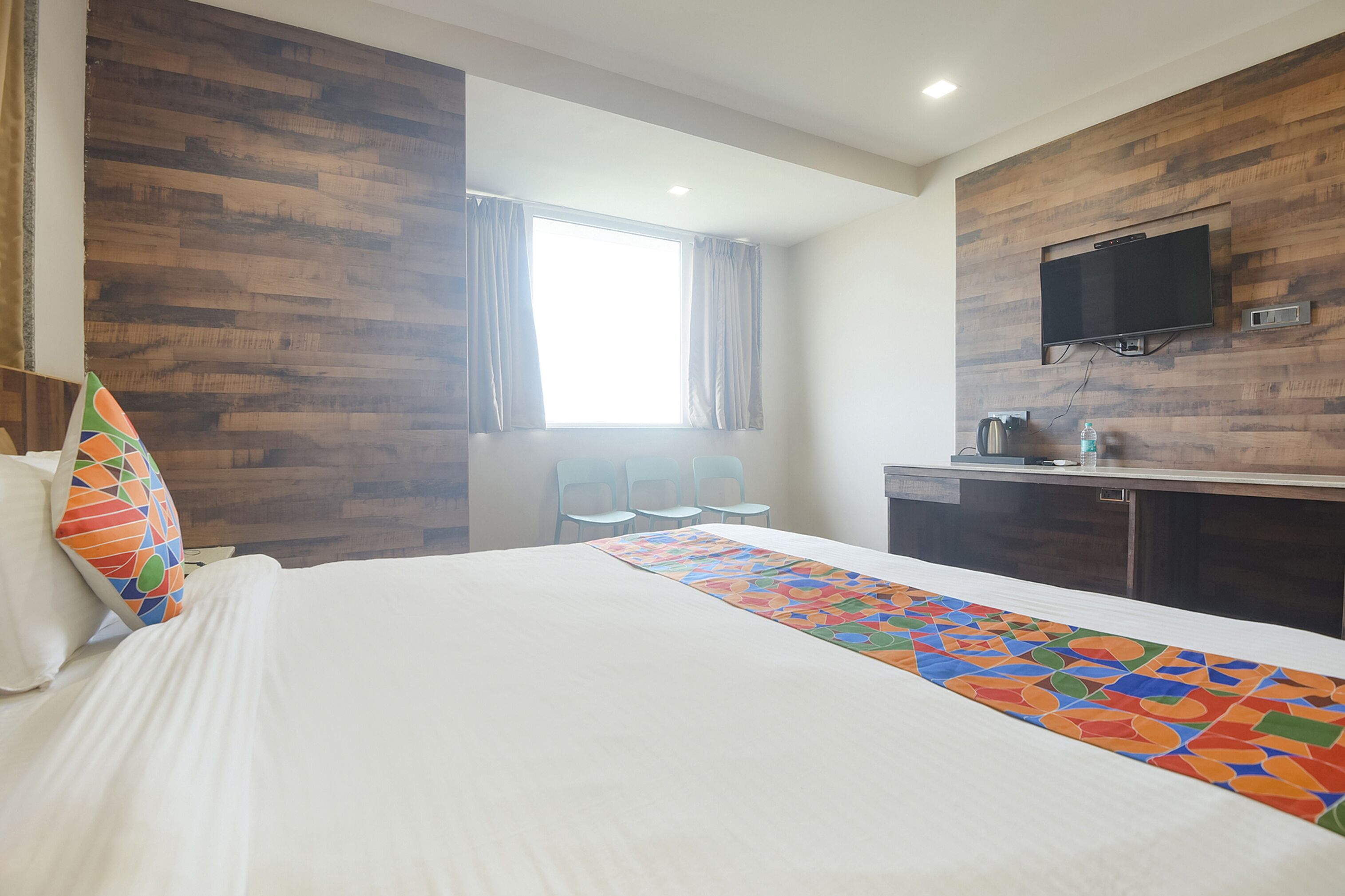 Habitación de hotel con una cama grande, un escritorio con televisor de pantalla plana y una ventana con cortinas.