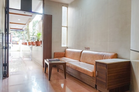 A modern lobby with a leather sofa, a wooden cabinet, and potted plants.