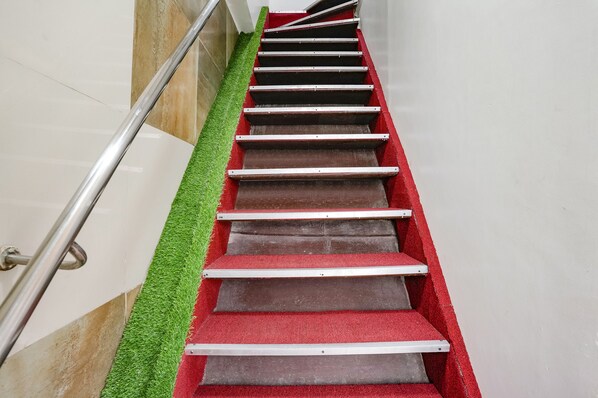 Uma escadaria com degraus revestidos de carpete vermelho e corrimãos de metal.