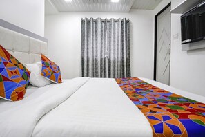 A neatly made bed with a white comforter and colorful geometric-patterned pillows.