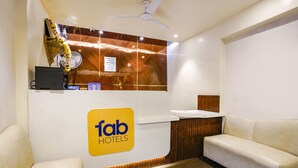 A reception area with a 'fab hotels' sign, a fan, a decorative item, and a seating area. - Fabhotel Springs Lodging (Mumbai)