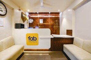 A reception area with a reception desk, a clock, a ceiling fan, and two sofas. - Fabhotel Springs Lodging (Mumbai)