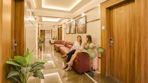 A hallway with a red sofa, wooden doors, and potted plants. - Fabhotel Springs Lodging (Mumbai)