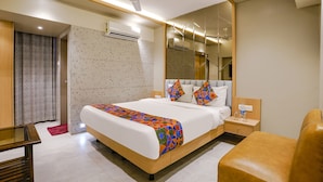 A modern hotel room with a large bed, bedside tables, a mirror, and a ceiling fan. - Fabhotel Springs Lodging (Mumbai)