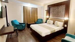 A hotel room with a bed, two chairs, a small table, and a curtain. - Fabhotel Prime Garden View (Jaipur)